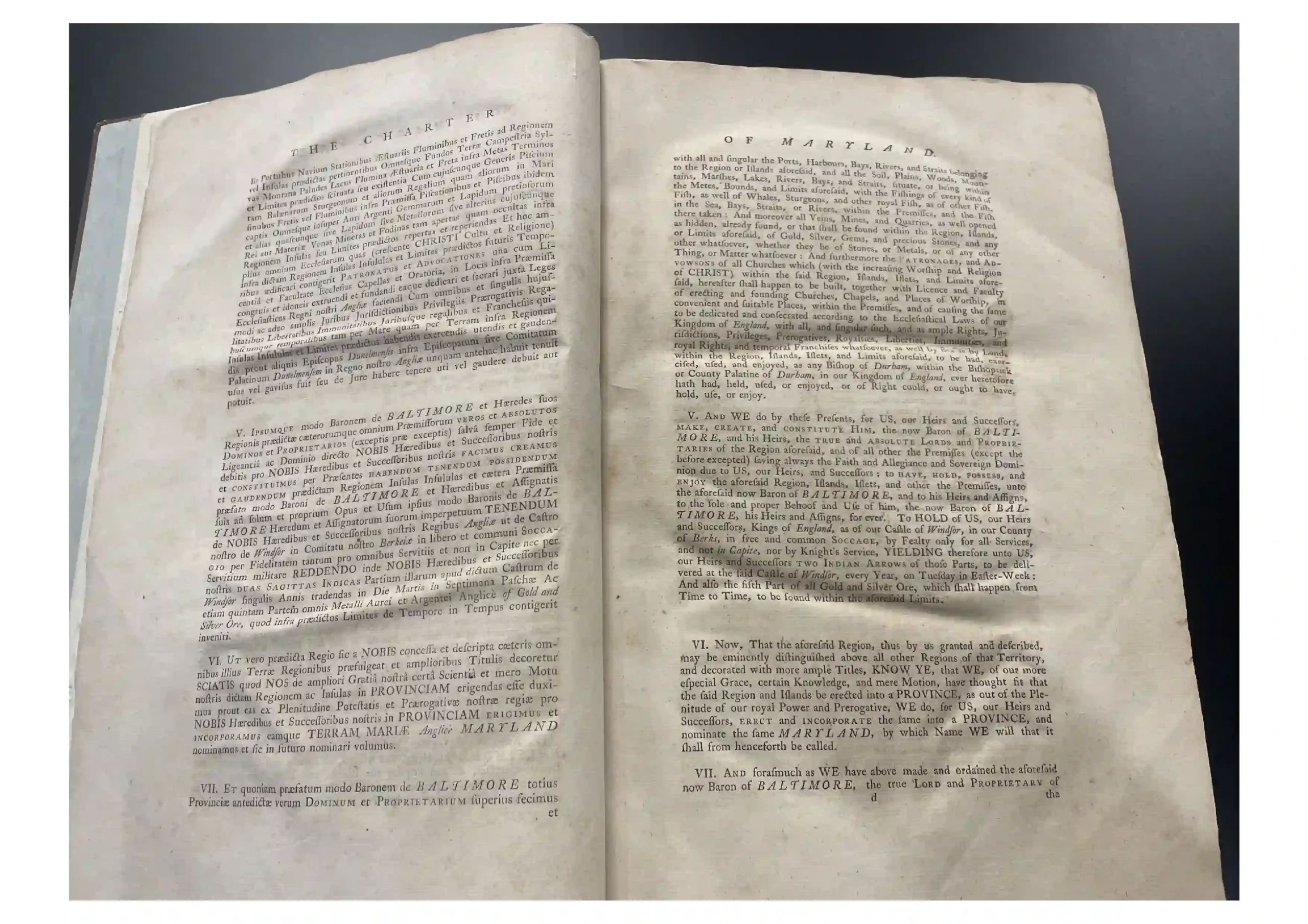 Open old book with two facing pages of dense Latin text, worn edges, lying on a dark surface