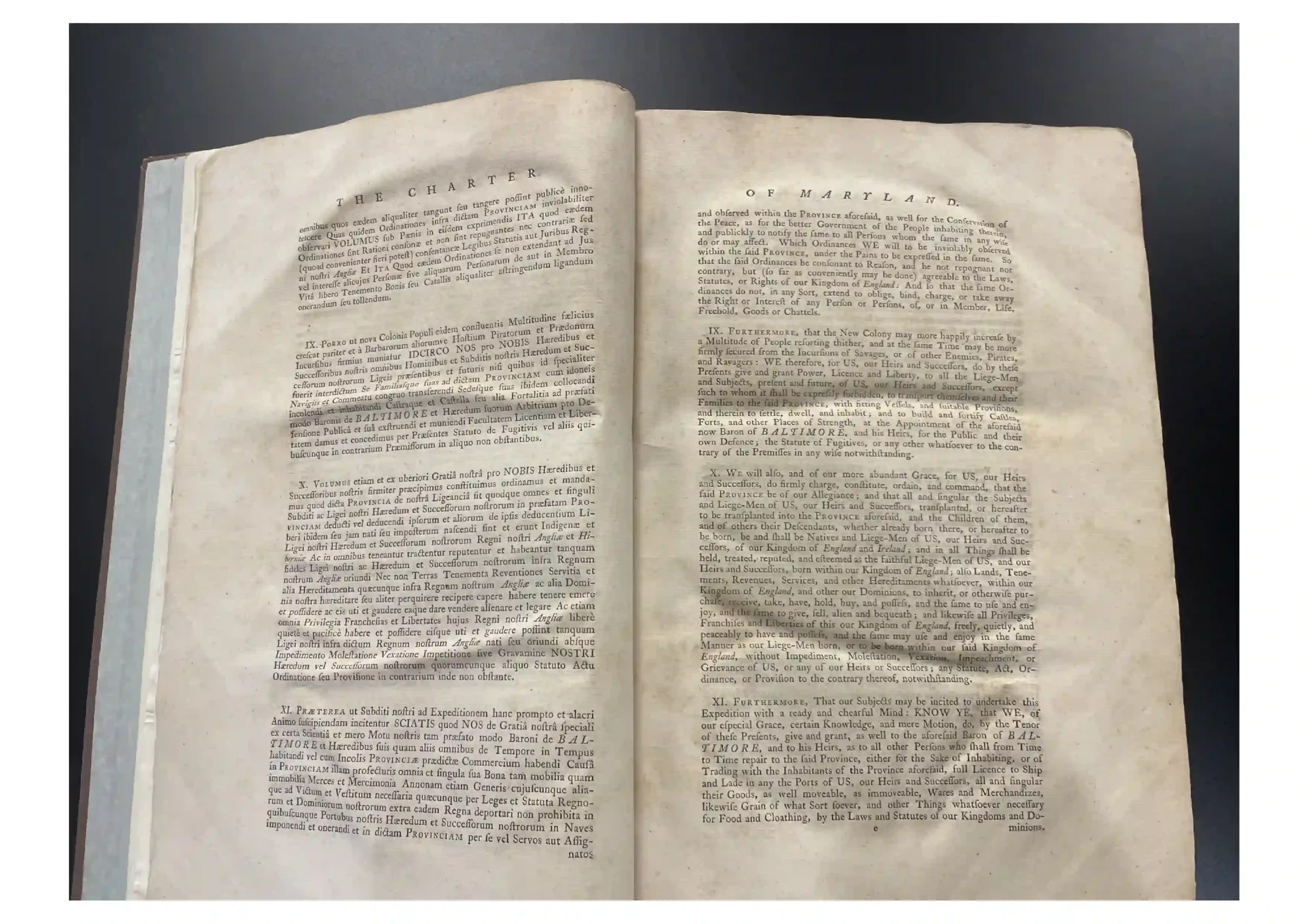 Open two-page spread of an antique book with dense small print on cream-colored pages against a dark background, laid flat.