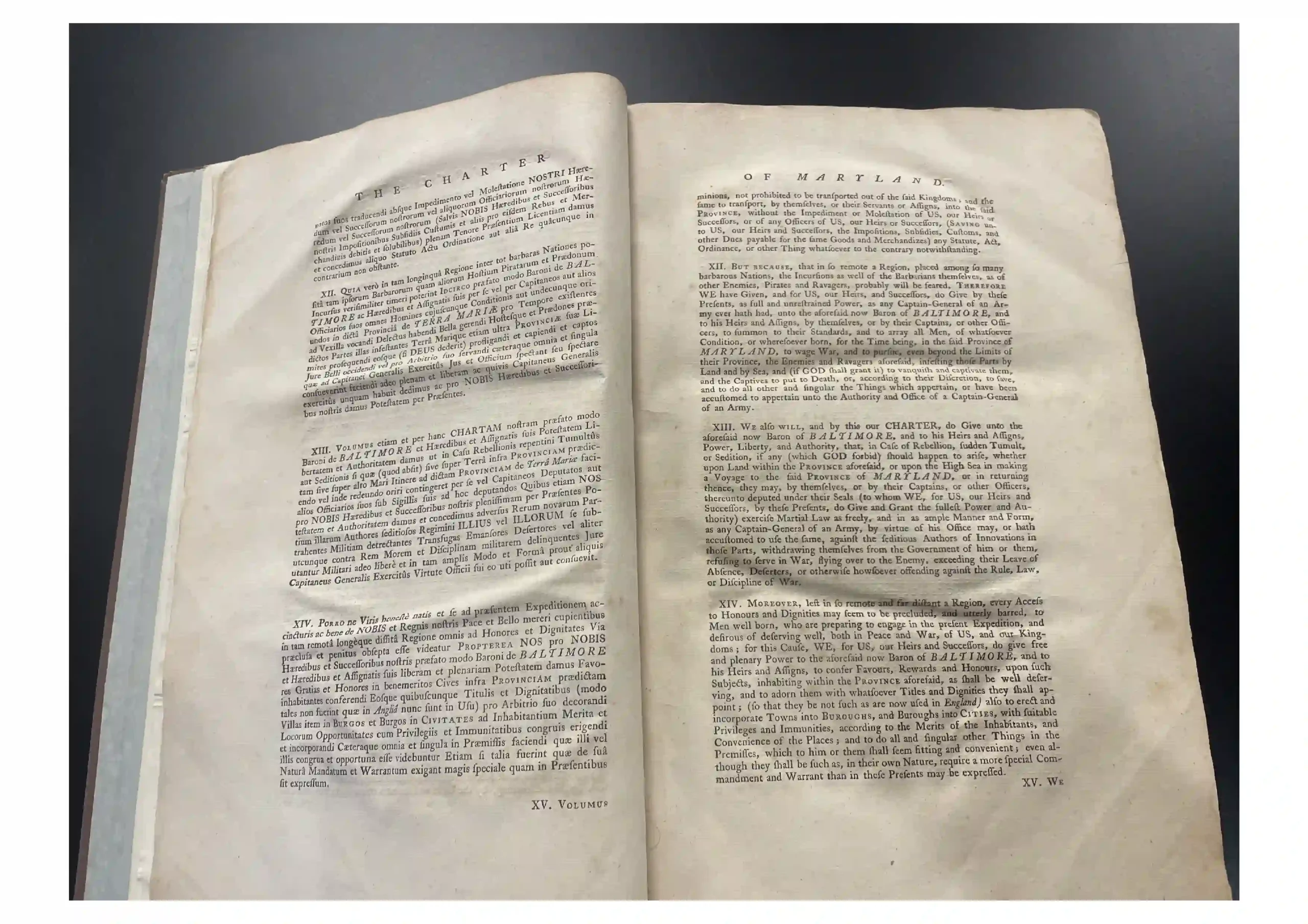 Open old book with two facing pages filled with dense small-print text; headers read 'THE CHARTER' on the left and 'OF MARYLAND' on the right, set against a dark background.