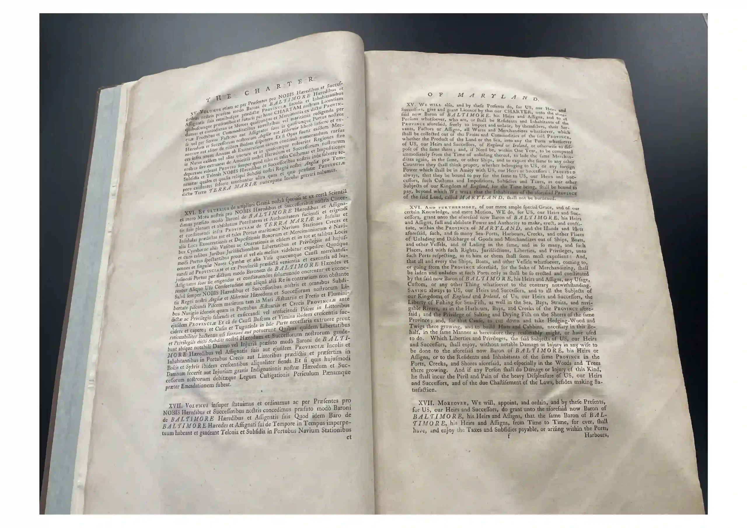Open two-page spread of an old book with dense small print and curved pages, laid on a dark surface.